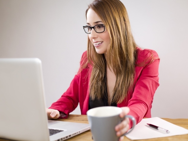 Деловая девушка в очках с ноутбуком и чашкой кофе