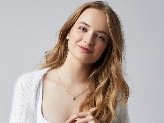 Нежная улыбающаяся голубоглазая девушка на сером фоне