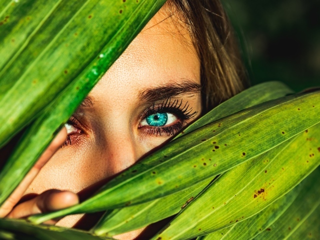 Девушка с голубыми глазами в зеленых листьях 
