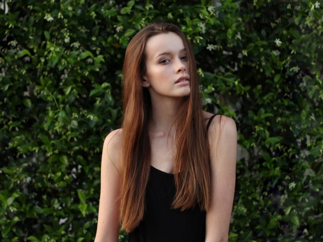 Длинноволосая шатенка на фоне зеленых зарослей