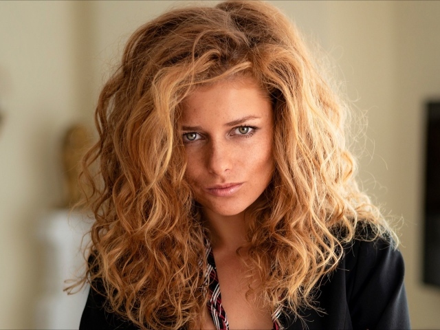 Рыжеволосая женщина с зелеными глазами в черном пиджаке