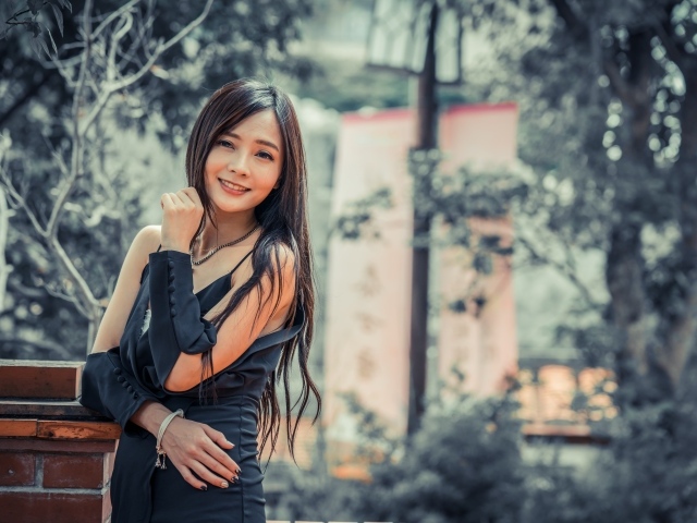 Улыбающаяся девушка азиатка в черном платье