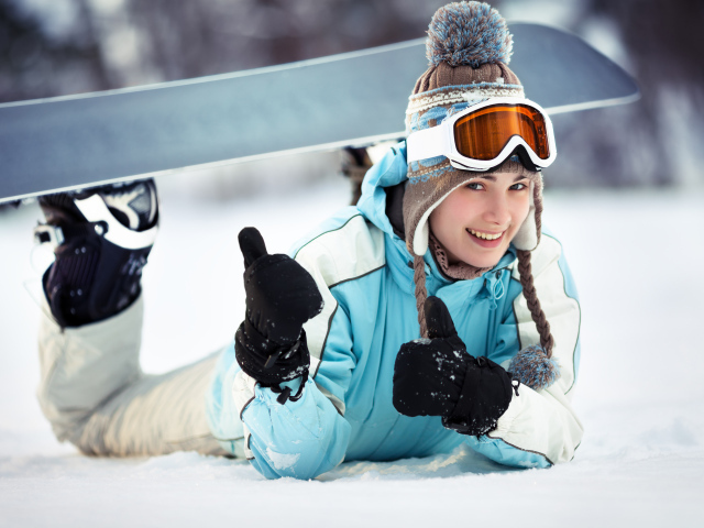 Улыбающаяся девушка сноубордистка на снегу зимой