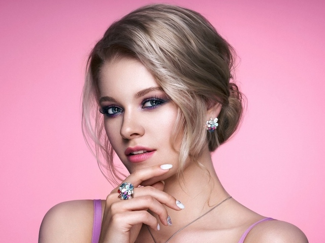 Стильная блондинка с прической на розовом фоне