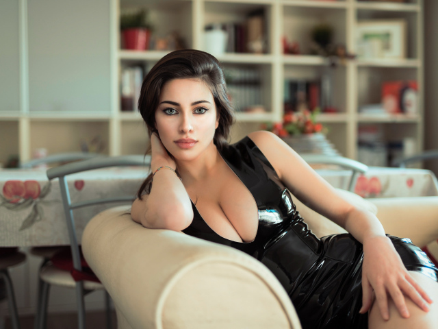 Стильная модная девушка в черном платье на диване