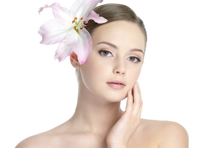 Нежная красивая девушка с лилией в волосах на белом фоне 