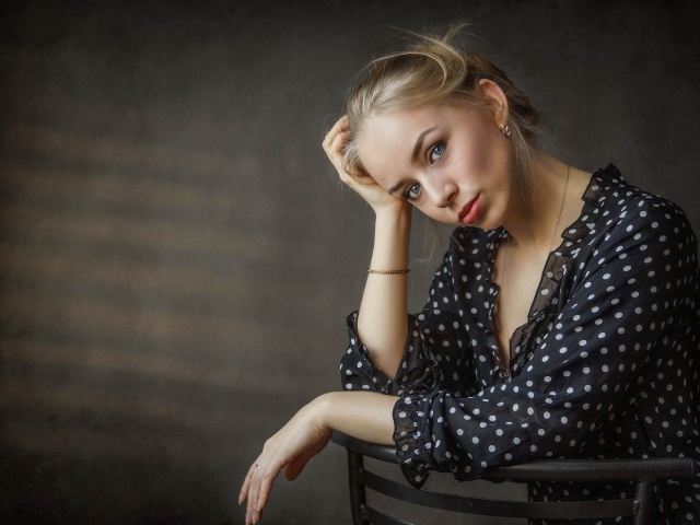 Нежная девушка блондинка сидит на стуле