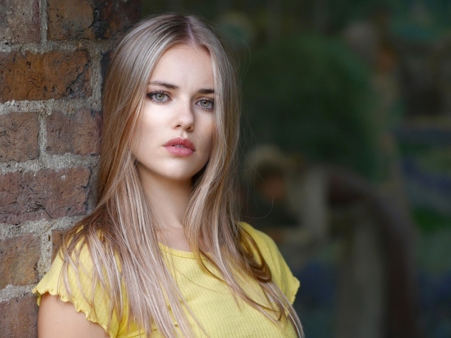 Грустный взгляд красивой светловолосой девушки у стены