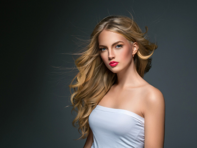 Молодая красивая голубоглазая блондинка на сером фоне