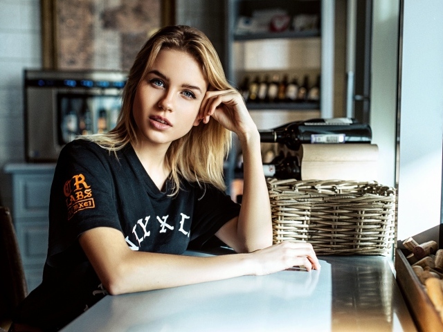 Молодая голубоглазая девушка сидит в кафе