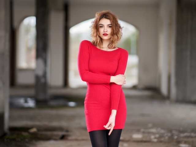 Молодая девушка в красном платье в старом здании