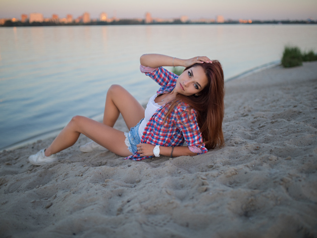 Молодая девушка лежит на песке у реки