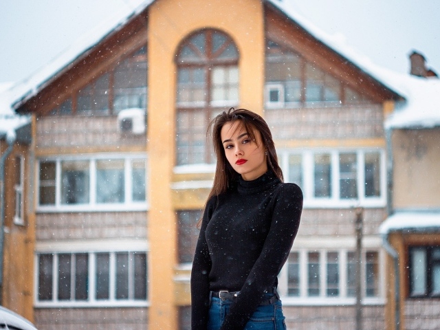 Молодая девушка на фоне заснеженного дома зимой