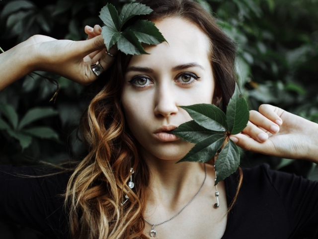 Молодая девушка с зелеными листьями в руках 