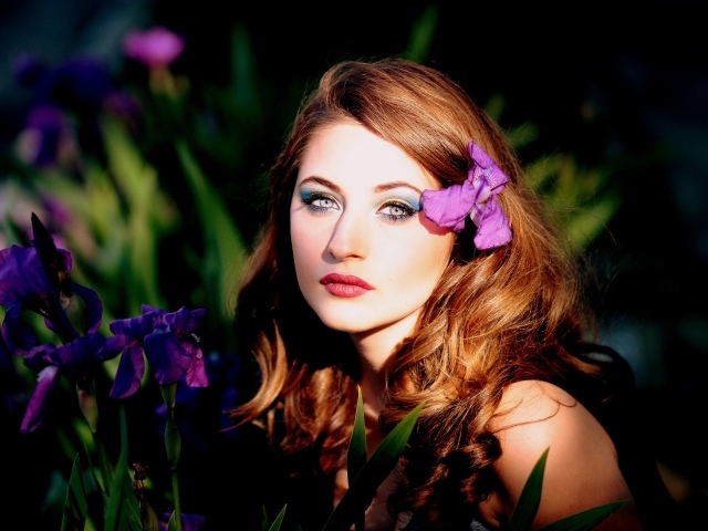 Молодая девушка с фиолетовым цветком ириса в волосах