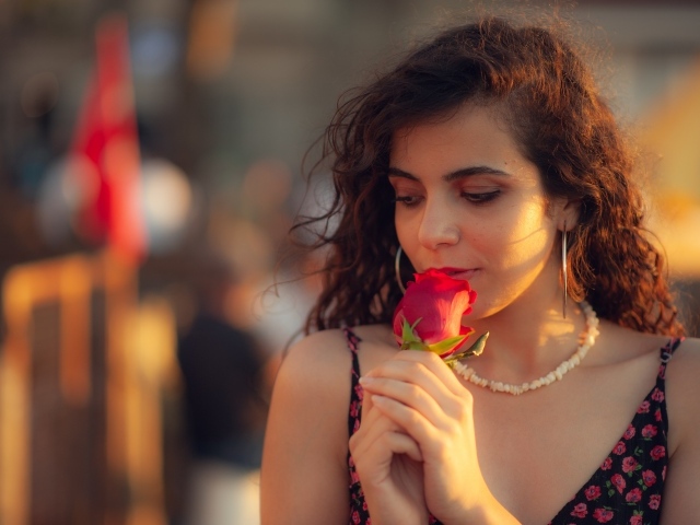 Молодая нежная девушка с красной розой в руке