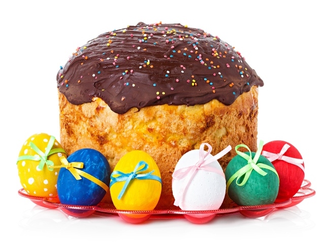Большой пасхальный кулич с шоколадной глазурью на белом фоне с крашеными яйцами 