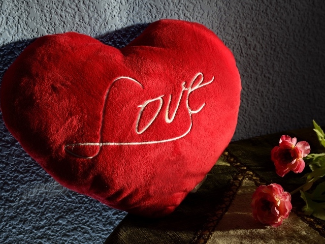 Большое плюшевое красное сердце у стены 