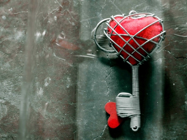 Ключ с красным сердцем на сером столе