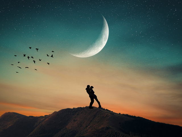 Влюбленная пара стоит на горе на фоне луны 
