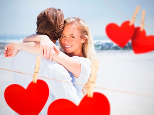 Влюбленная пара с красными сердечками на берегу океана