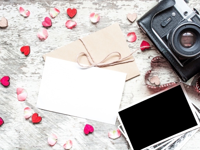 Старый фотоаппарат с фотографиями и маленькими сердечками на столе