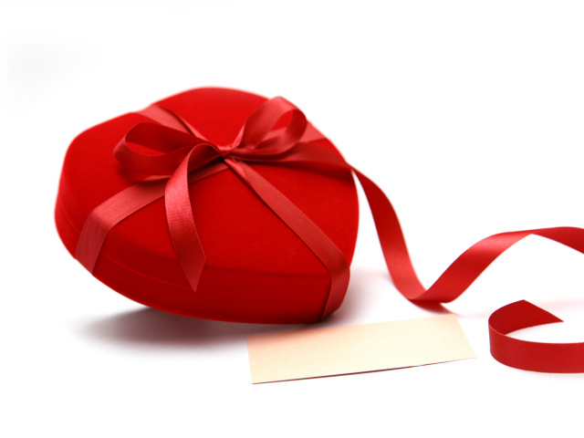 Красная коробка для ювелирных изделий в форме сердца на белом фоне 