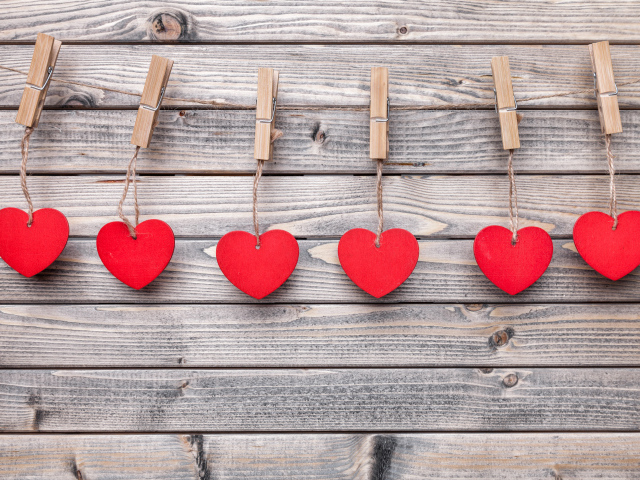 Красные сердечки на прищепках на деревянном столе 