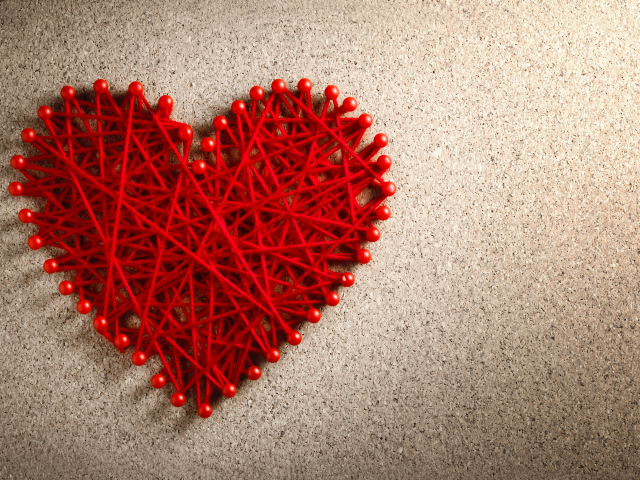 Сердце из красных нитей и невидимок на сером фоне