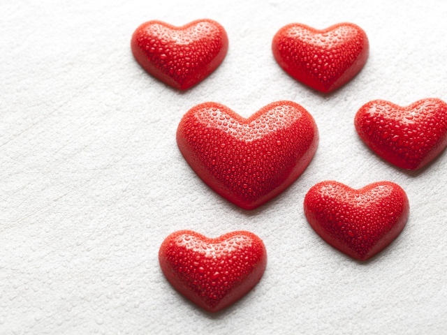 Мокрые красные сердечки на белой поверхности 