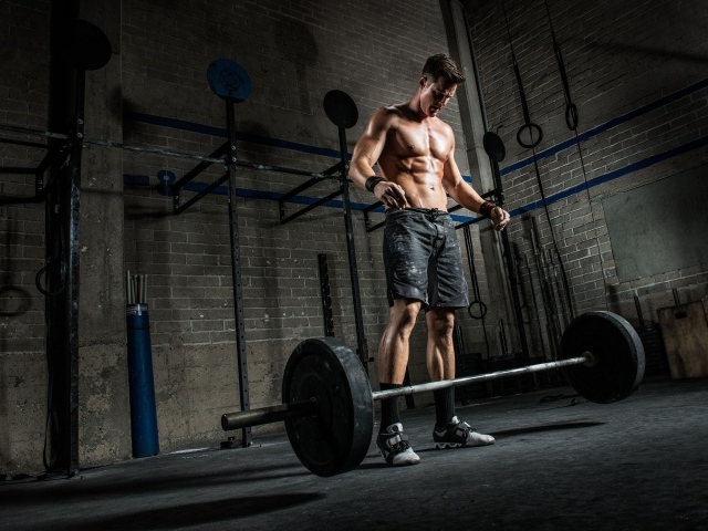Мужчина спортсмен поднимает штангу в спортзале