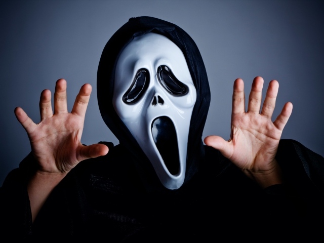 Мужчина в маске пугает на сером фоне