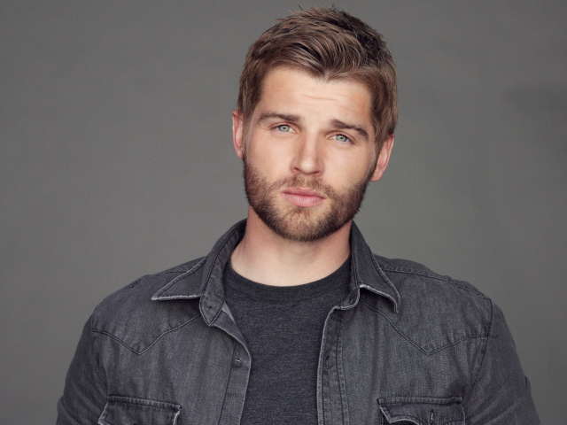 Молодой мужчина, американский актер Майкл Фогель на сером фоне