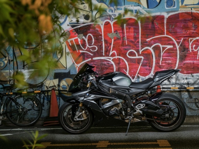 Черный мотоцикл BMW S1000RR на фоне разрисованной стены