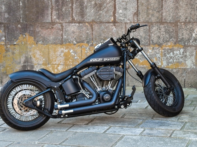 Черный стильный мотоцикл Harley-Davidson на фоне стены