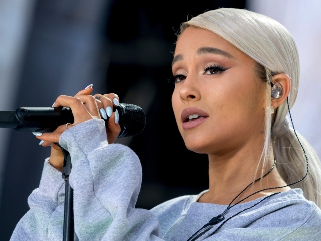 Светловолосая певица Ариана Гранде с микрофоном на сцене 