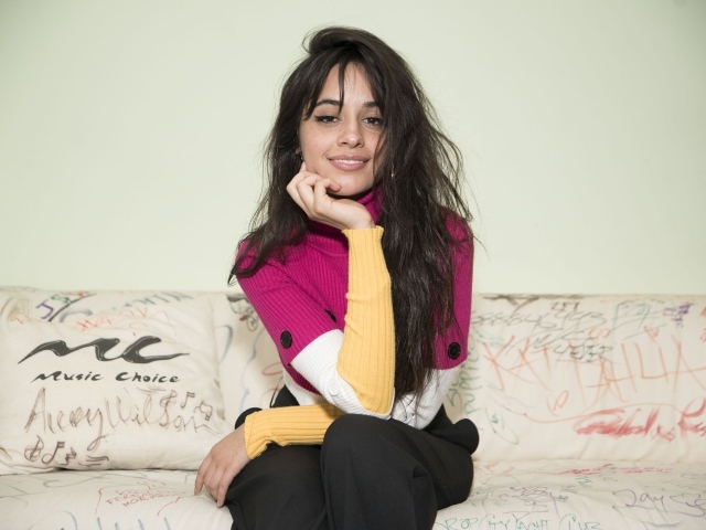 Улыбающаяся Камила Кабельо сидит на диване