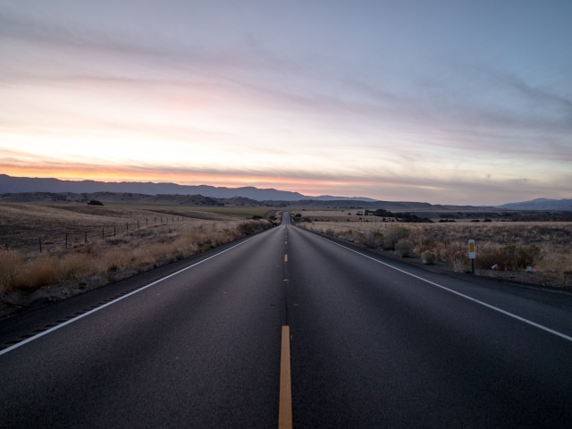 Асфальтная дорога уходит вдаль на фоне неба