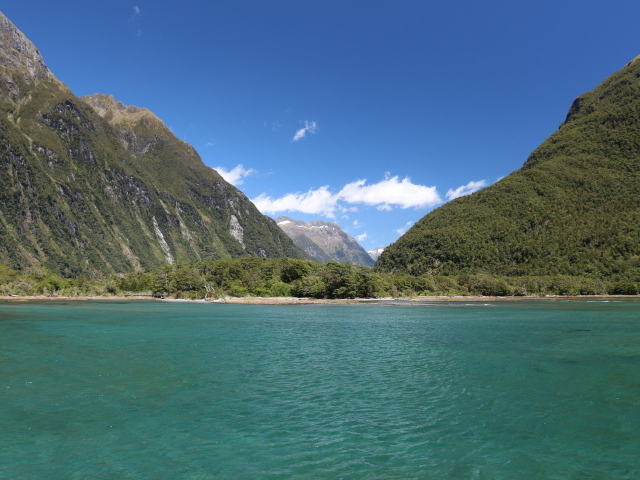 Голубая вода в озере на фоне покрытых зеленью гор под голубым небом