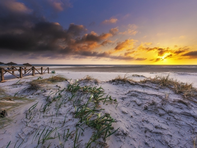 Белый песок в траве на берегу под красивым небом на закате