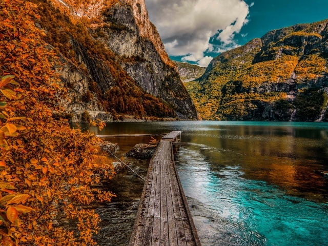 Деревянный мост в воде на фоне гор 