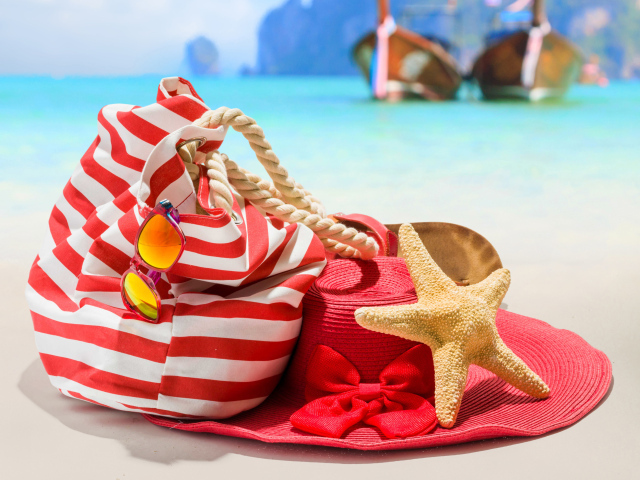 Большая красная шляпа с сумкой и морской звездой на пляже