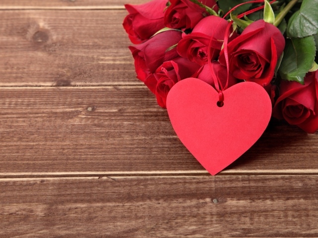 Букет красных роз на деревянном столе с красным сердцем
