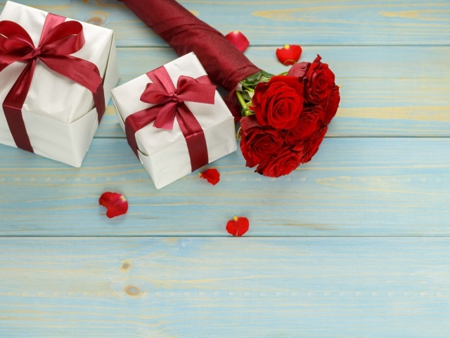 Букет красных роз с подарками на столе