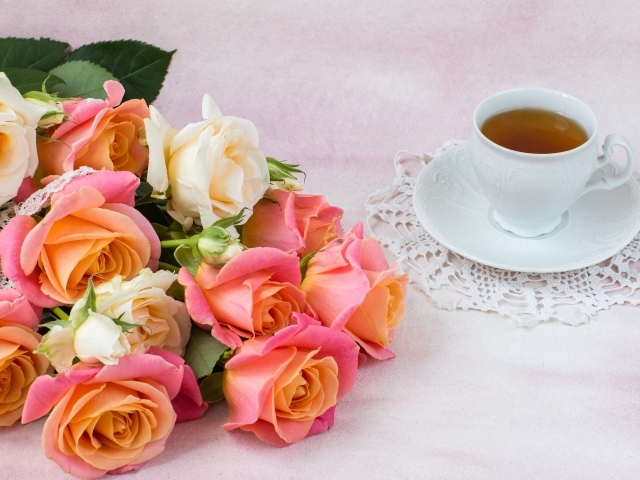 Красивый букет нежных роз на столе с чашкой чая