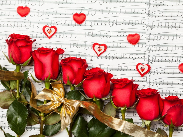 Красивые красные английские розы лежат на нотной тетради
