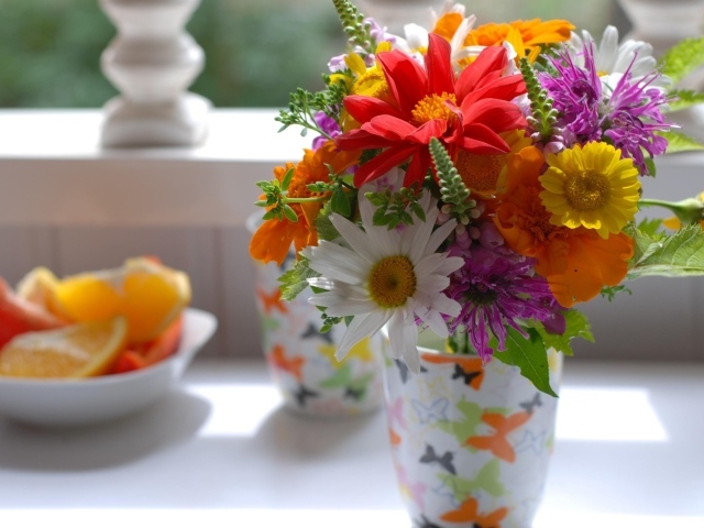 Букет разноцветных  садовых цветов в вазе на столе 