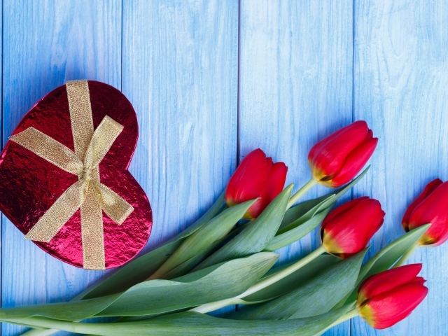Букет красных тюльпанов на синем фоне с подарком в форме сердца