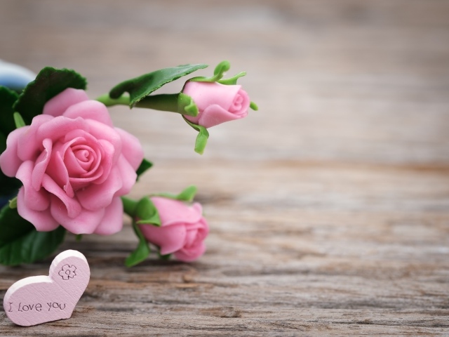 Розовые искусственные розы с сердцем на деревянном фоне