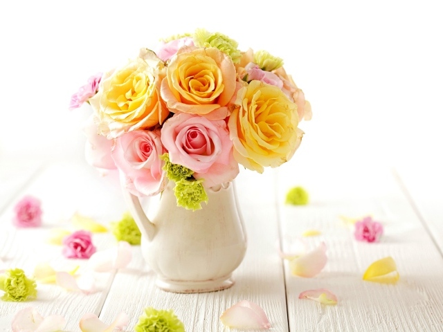 Желтые и розовые розы в вазе на столе 
